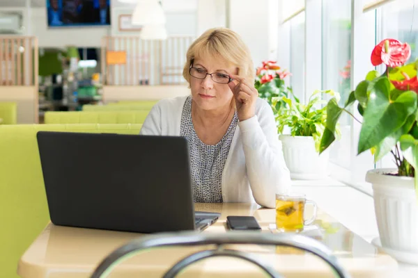 Ofisteki bir kafede dizüstü bilgisayarı olan bir kadın, serbest çalışan ve iş adamıdır.