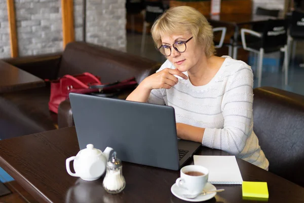 Ofisteki bir kafede dizüstü bilgisayarı olan bir kadın, serbest çalışan ve iş adamıdır.