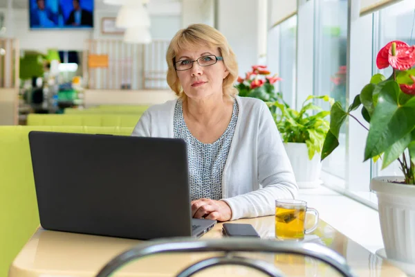Uma mulher com um laptop trabalha em um café no escritório, ela é freelancer e empresária. — Fotografia de Stock