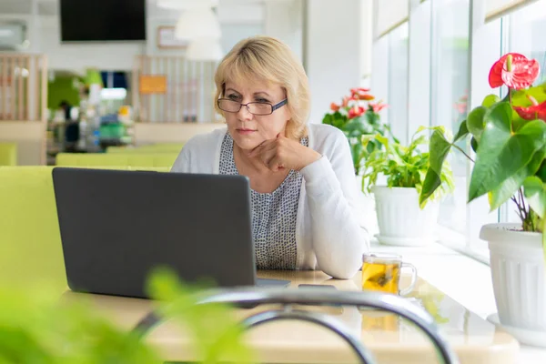 Uma mulher com um laptop trabalha em um café no escritório, ela é freelancer e empresária. — Fotografia de Stock