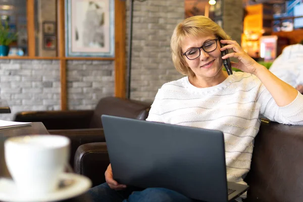 Una mujer con un portátil trabaja en un café en la oficina, es freelancer y un hombre de negocios — Foto de Stock