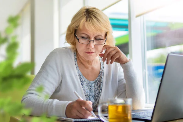 Ofisteki bir kafede dizüstü bilgisayarı olan bir kadın, serbest çalışan ve iş adamıdır.