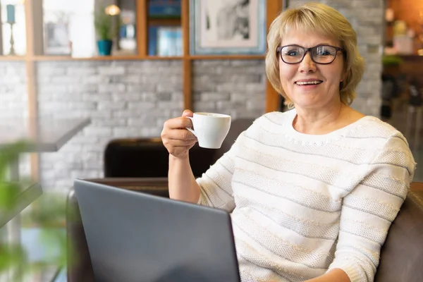 En kvinna med laptop jobbar på ett café på kontoret, hon är frilansare och affärsman. — Stockfoto