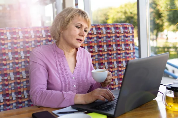 Uma mulher com um laptop trabalha em um café no escritório, ela é freelancer e empresária. — Fotografia de Stock