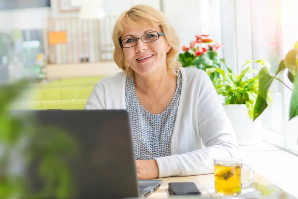 Mulher com um laptop trabalha em um café no escritório, ela é freelancer . — Fotografia de Stock