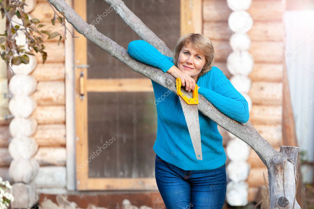Woman in autumn works in the garden and cleaning leaves.