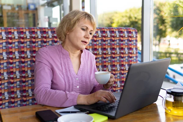 Женщина с ноутбуком работает в кафе в офисе, она фрилансер и бизнесмен — стоковое фото