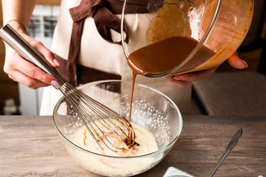 Odaklanmayı seç. Kek tatlısı için malzemeler sevecen ve koyu ahşap arka planda. Kadınların elleri krem hazırlar..