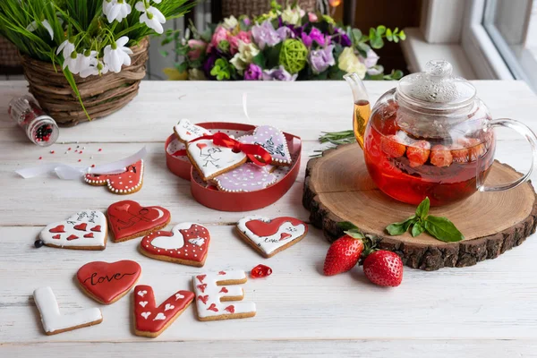 Select focus. Cakes created by the owner for congratulations. Cookies in the form of hearts and letters of love. Dessert on the table with a glass teapot made of red berries