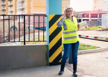 Kadın bir inşaat işçisi şantiyede. Projesi olan orta yaşlı bir kadın evi kontrol ediyor..