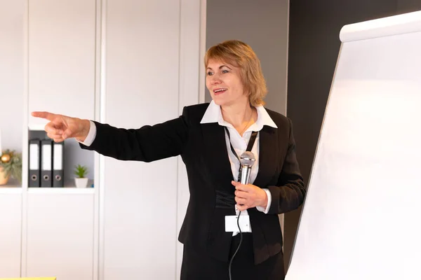 A business woman makes a presentation in a conference room with training. A middle-aged woman conducts training courses