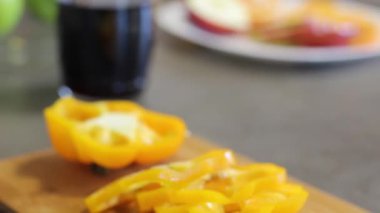 Ahşap tahta üzerinde yalan sarı biber, yuvarlak parçalar. Aksesuarlar ile mutfak masası. Sebzeleri kes. Yemek yemek. Close.