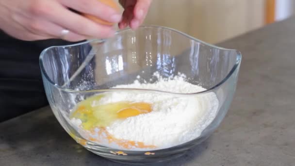 小麦粉や卵の他の黄身である丸い ガラス 透明なプレートで卵を破ります 男は台所で食べ物を調理します — ストック動画