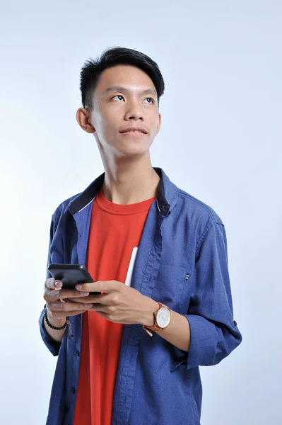 Potrait z hezkého mladého asijského muže, který drží chytrý telefon a my — Stock fotografie