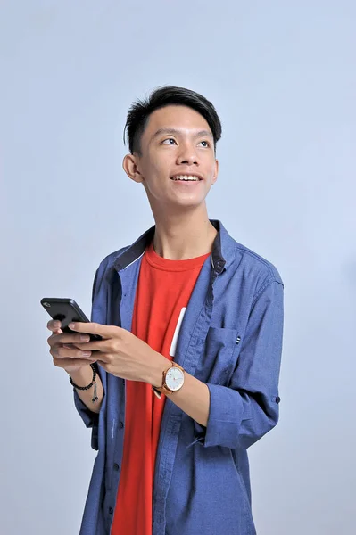 Potrait de beau jeune homme asiatique tenant un téléphone intelligent et nous — Photo