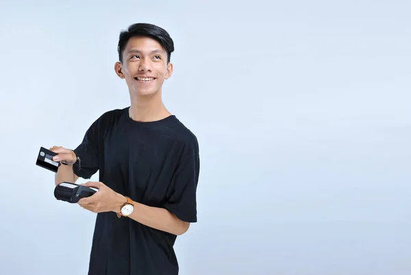 Mladý asijský muž si odplavit kreditní kartu/debetní kartu a hledal — Stock fotografie