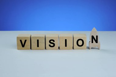 Ahşap küp üzerine yazılmış vizyon kelimesi. Mavi arka planlı