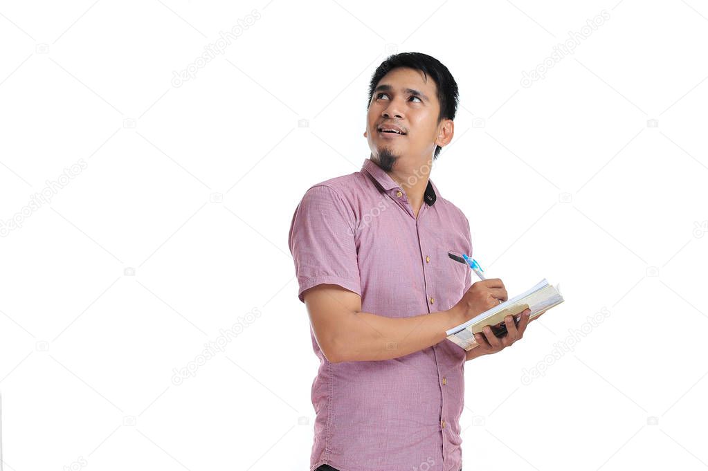 Asian male writing on his notebook look at blank area or copy sp