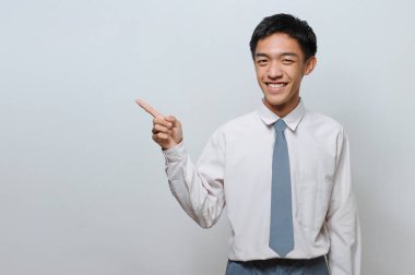 Endonezyalı Kıdemli Öğrenci üniforması giyip fotokopi alanına veya boş alana bakıyor, gri arkaplanda izole edilmiş.