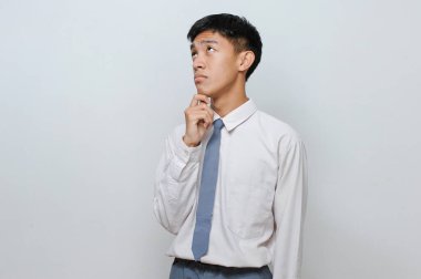 Endonezyalı lise üniforması giyen zeki bir öğrencinin portresi gri arka planda izole edilmiş bir fikir arıyor.