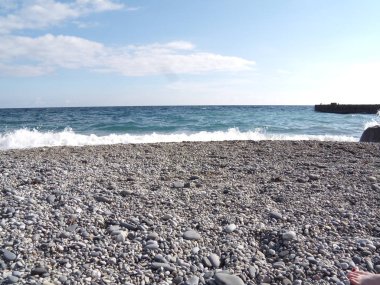 Dalgalar ve deniz insıçrı. Sahilde taşlar ve kabuklar.