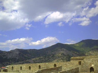 Ceneviz kalesinin eski taş duvar duvarlarına, Sudak yakınlarındaki Ceneviz kalesine, eski kaleye, eski kaleye, yeşil çimenve mavi gökyüzüne, dağlara, taşlara, kayalara, Kırım'a bak.