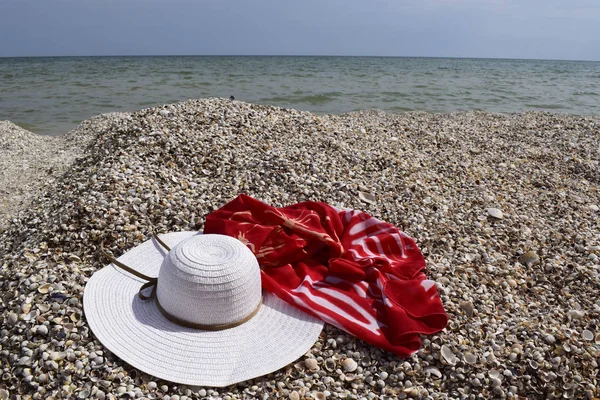 Vintage summer straw beach hat and pareo on the seashore.