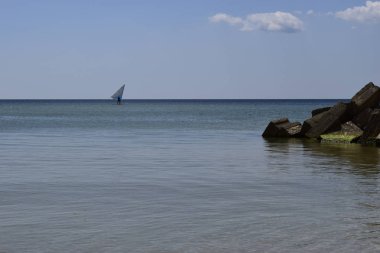Rüzgar sörfçüsü genç adam deniz suyunda rüzgar sörfü yapıyor