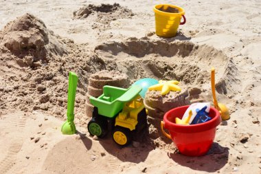 Çocukların plaj oyuncakları güneşli bir kum üzerinde.