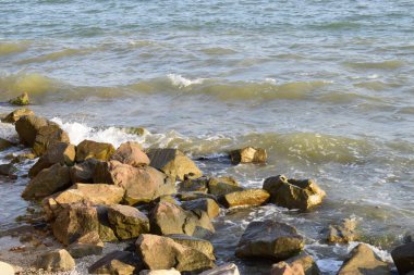 Sahilde deniz sörfü ve kayalar. Isleski taşlar ve dalgalar
