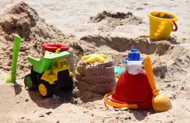 Çocukların plaj oyuncakları güneşli bir kum üzerinde.