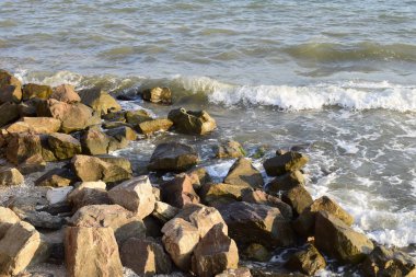 Sahilde deniz sörfü ve kayalar. Isleski taşlar ve dalgalar