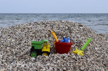 Denizin arka planında kum için plastik çocuk oyuncakları.