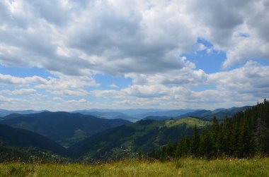 Dağların yeşili arasında kıvırcık beyaz bulutlar