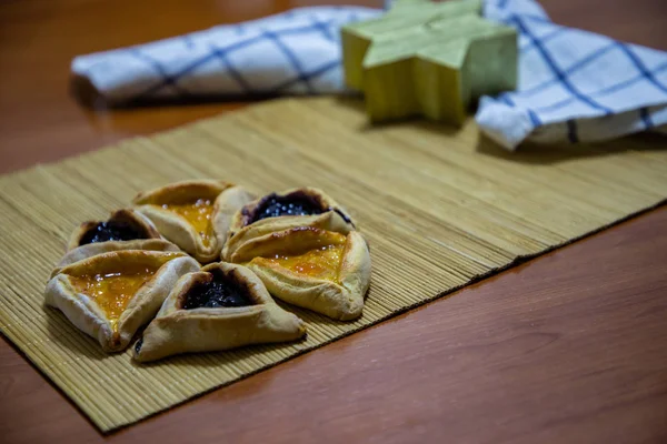 Hamantash Purim biscoitos de mirtilo e geléia de damasco com fundo de mesa de madeira e vela em forma de estrela David — Fotografia de Stock