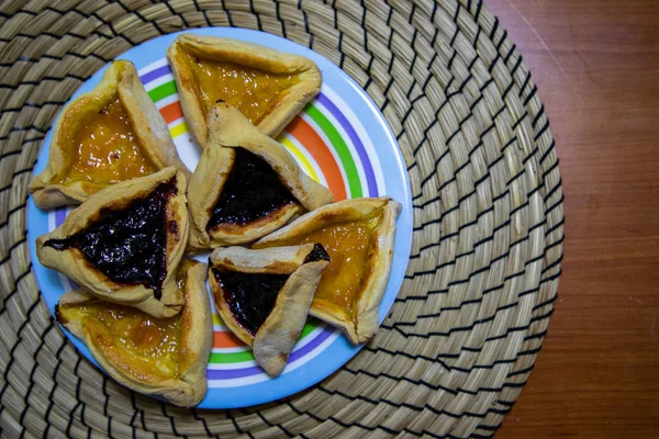 Hamantash Purim blåbär och aprikos sylt cookies i färgade plattan med trä bordsbakgrund — Stockfoto