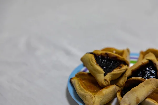 Hamantash Purim biscoitos de mirtilo e geléia de damasco em pla colorido — Fotografia de Stock