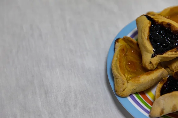 Hamantash Purim blåbär och aprikos sylt cookies på färgade pla — Stockfoto