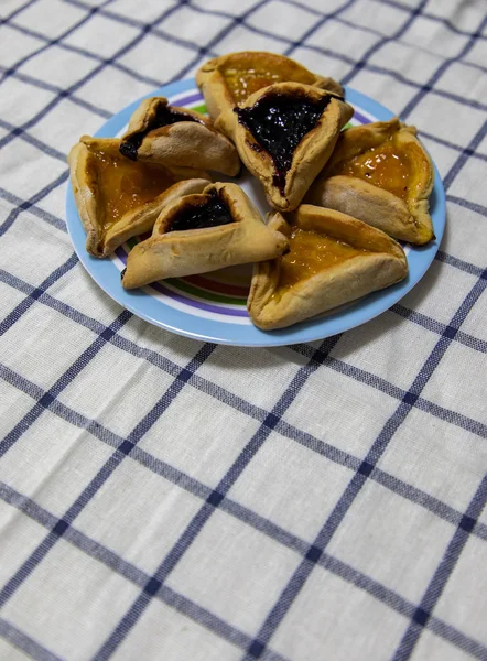 Hamantash Purim Blueberry e geléia de damasco biscoitos na placa colorida na toalha de mesa com fundo azul quadrados — Fotografia de Stock