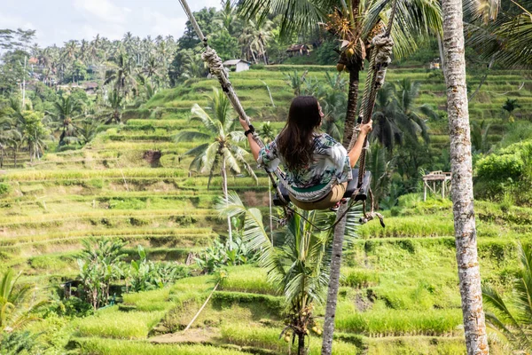 Mooie vrouw op hoge Swing boven rijstvelden in Bali — Stockfoto