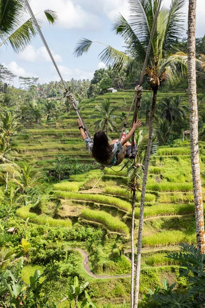 Mooie vrouw op hoge Swing boven rijstvelden in Bali — Stockfoto
