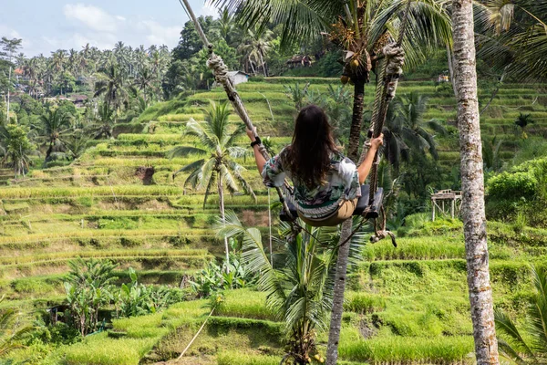 Mooie vrouw op hoge Swing boven rijstvelden in Bali — Stockfoto