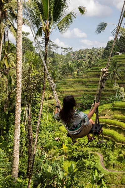 Mooie vrouw op hoge Swing boven rijstvelden in Bali — Stockfoto