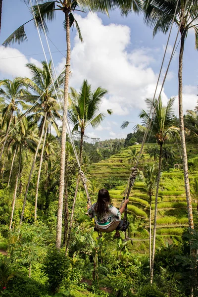 Mooie vrouw op hoge Swing boven rijstvelden in Bali — Stockfoto