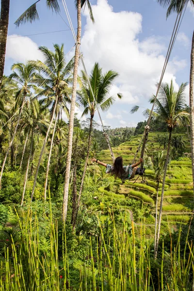 Mooie vrouw op hoge Swing boven rijstvelden in Bali — Stockfoto