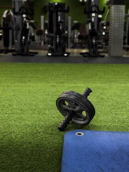 Abs wheel on green artificial grass and blue training mat — Stockfoto