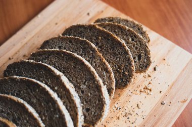 Evde ahşap kesme tahtası üzerinde dilimlenmiş çok tahıllı ev yapımı ekmek