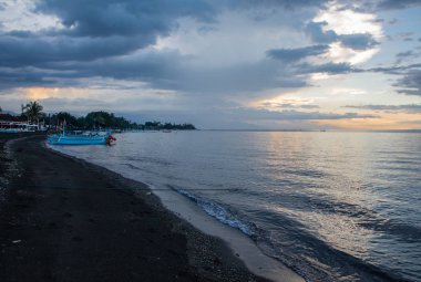 Bali boa ile sakin okyanus ve siyah kum plaj üzerinde Mavi saat