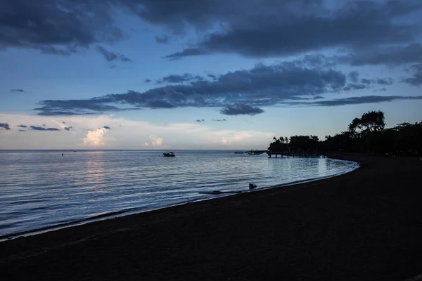 Blue hour over calm ocean and black sand beach