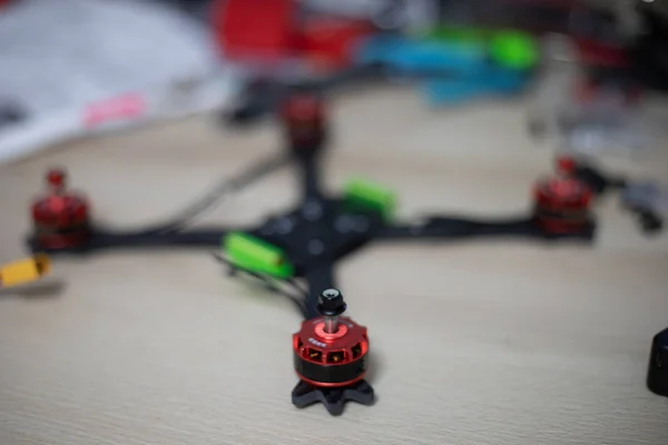 Telaio drone racing con motori montati su tavolo in legno con utensili sfocati sullo sfondo — Foto Stock